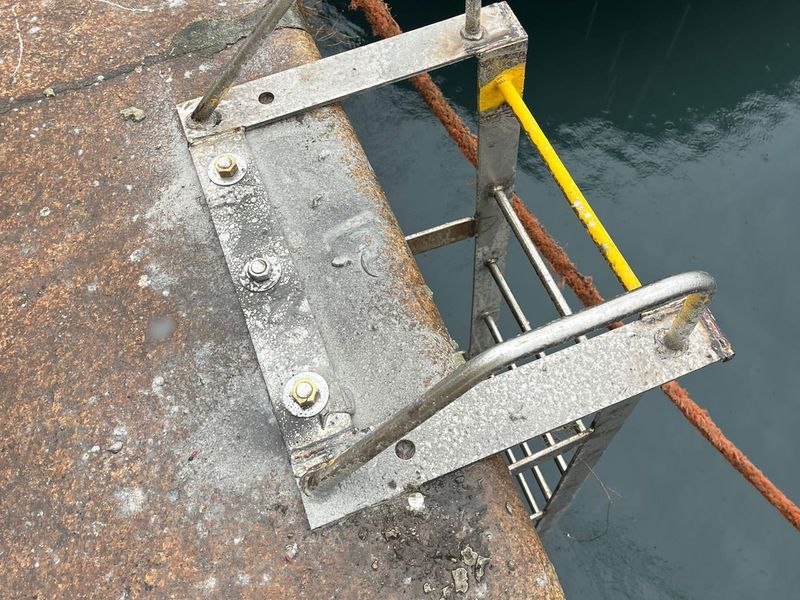 Scaletta in acciaio inox imbullonata al ciglio della banchina, sopra l’acqua